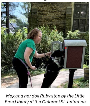 Meg and her dog Ruby looking at books in the Little Free Library outside of Falls Library