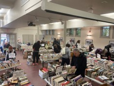 People looking at tables of books during the spring book and bake sale
