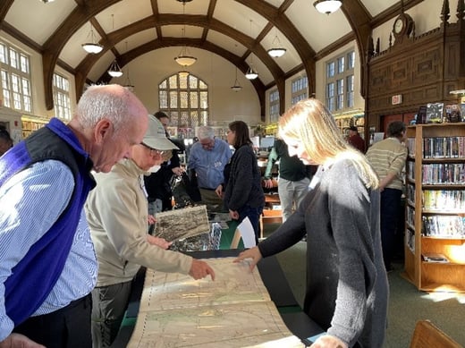 Photo of a white man and white woman looking at historic maps