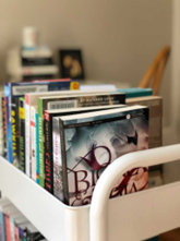 White cart with a variety of books on top.