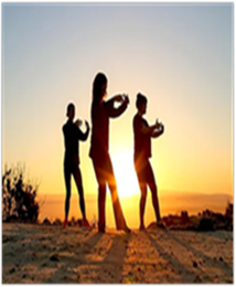 Photo of people engaging in qigong outdoors in front of a setting sun